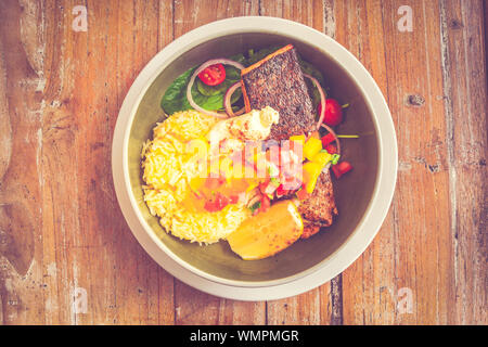 Salmone ciotola di riso Riso di noce di cocco o di riso al burro, filetto di salmone alla griglia, baby insalata di spinaci, cipolla rossa, mango di salsa di pomodoro, panna acida, cuneo di limone Foto Stock