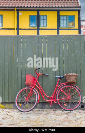 Red bicicletta contro un recinto verde nella parte vecchia di Ribe, Danimarca Foto Stock