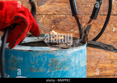 Lavoratore con Red Glove per proteggere la scintilla di luce con processo di saldatura con tubo blu metallico e luminose scintille in acciaio Foto Stock