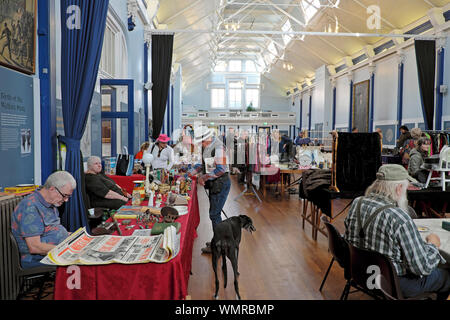 Lewes hall del mercato interno di commercianti che vendono mercanzia & man con il cane cercando di antiquariato in stallo in giorno di mercato nella città di Sussex England Regno Unito KATHY DEWITT Foto Stock