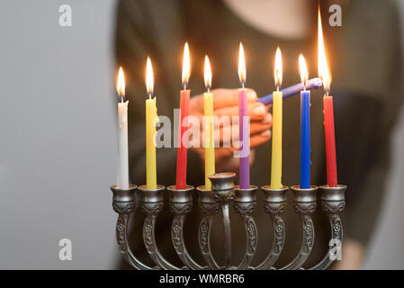 Donna ebrea Hanukkah illuminazione candele in un menorah. Persone festeggiano Chanukah accendendo candele su una menorah, chiamato anche Hanukiyah. Ogni notte, ancora una candela è accesa. Foto Stock