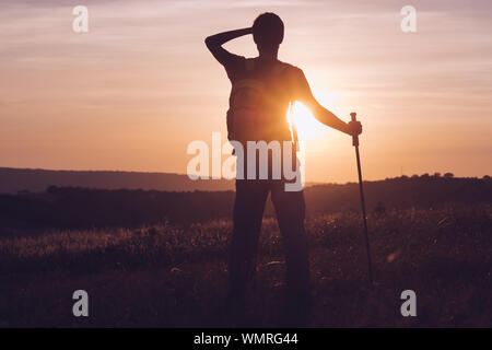 Silhouette di un campione di alta montagna. Lo sport e la vita attiva. Silhouette escursionista uomo tracking con zaino e trekking pole, Foto Stock