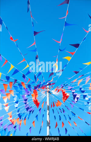 Colorato bunting attaccato ad un palo visto contro un luminoso cielo blu. Foto Stock