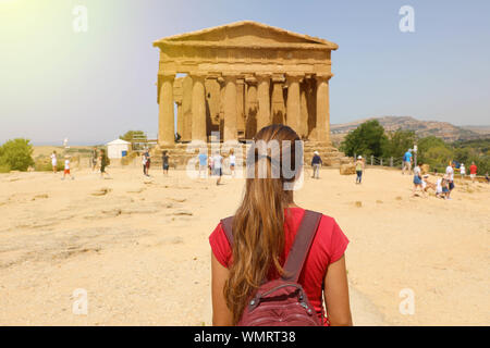 Giovane donna guarda al Tempio Concordia nella Valle dei Templi di Agrigento e la Sicilia. Traveler ragazza visite templi greci in Italia Meridionale in precedenza Foto Stock