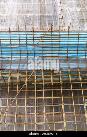Impalcature di bambù con rete di sicurezza al grattacielo Sito in costruzione Foto Stock