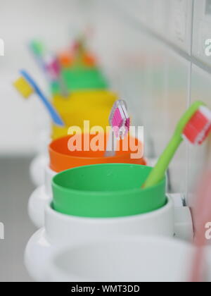 Close-up di spazzolini da denti colorati in contenitori a bagno