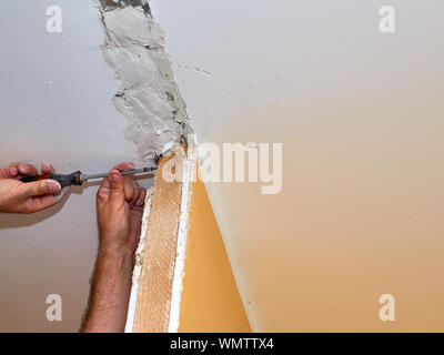 Uomo di elementi di fissaggio con una vite in una parete durante lavori di ristrutturazione in un appartamento Foto Stock