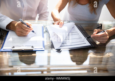 Due colleghi di lavoro seduto alla scrivania lavorando insieme in ufficio Foto Stock