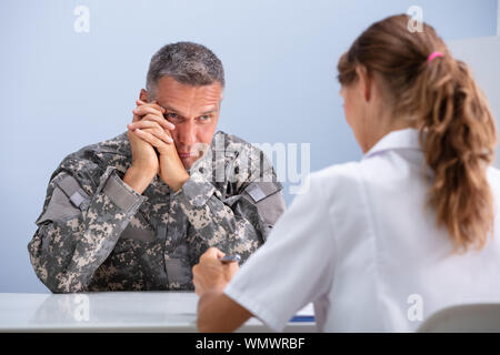 Close-up di premuto soldato dell'esercito che soffrono di Ptsd durante la sessione di psicoterapia a Doctor's Clinic Foto Stock