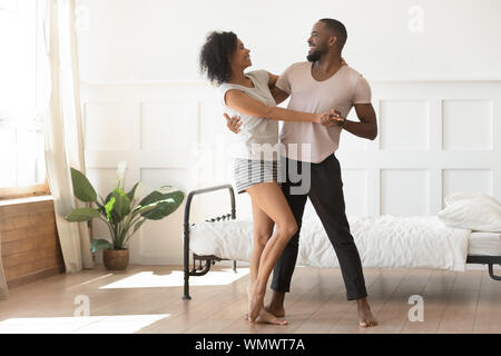 Felice famiglia americana africana coppia danzante in camera da letto. Foto Stock