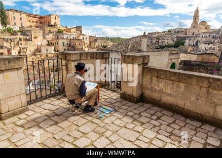 In Italia, Basilicata, provincia di Matera, Matera. Maggio 28, 2019. Un artista su un tetto di verniciatura di un acquerello di vista della città, dominata dalla cattedra Foto Stock