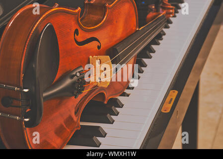 Il violino è sdraiato su un pianoforte, chiudere l'immagine a colori in stile opaco Foto Stock