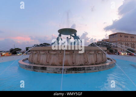 La fontana del Tritone nella città capitale di Valletta, Malta appena prima del tramonto. Foto Stock