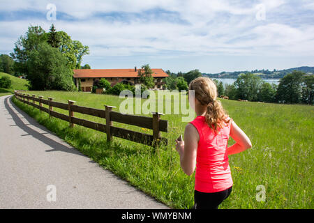 Il sentiero intorno al lago nelle alpi bavaresi della Germania. Montare la donna corre lungo il percorso. Foto Stock