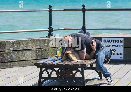 Un paio di godere di uno sfrontato bacio in pubblico in una calda giornata estiva nel Regno Unito. Foto Stock