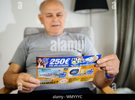 Parigi, Francia - 22 Maggio 2019: Senior man holding flyer pubblicità che presentano sul coperchio il televisore Panasonic e AEG lavatrice offerti da esperti Oehler Foto Stock