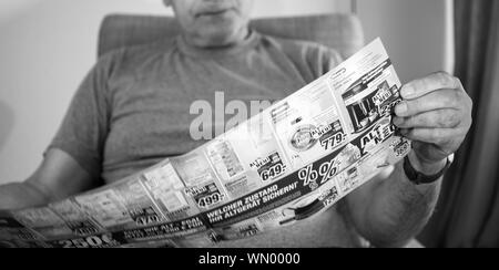 Parigi, Francia - 22 Maggio 2019: Senior man holding flyer pubblicità che presentano sul coperchio di più prodotti domestici offerti da esperti Oehler - macchine di lavaggio, expressos, frigoriferi, ferro da stiro Foto Stock