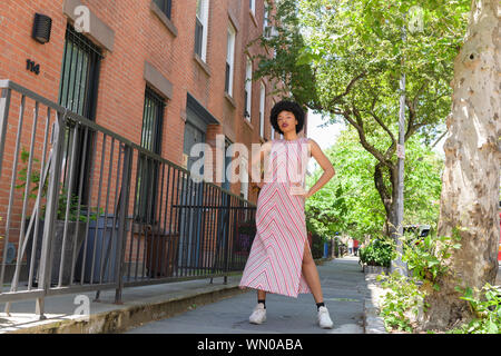Donna che indossa abiti a strisce da case in mattoni Foto Stock