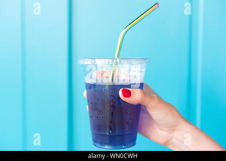 Donna blu holding drink in una tazza di plastica con paglia di metallo Foto Stock