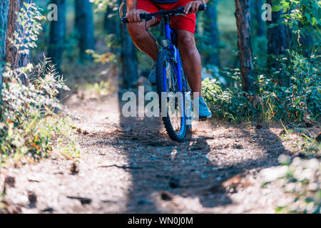 Vecchio Uomo sovrappeso corse in mountain bike attraverso il bosco con estrema fatica. Foto Stock