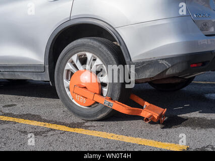 Auto parcheggiata immobilizzato con orange morsetto di parcheggio o di boot Foto Stock