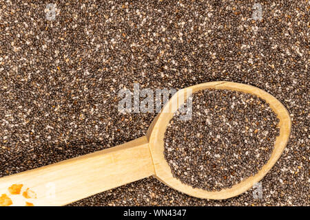 Close-up texture di un mucchio di chia semi in un cucchiaio di legno con il fuoco selettivo. Foto Stock