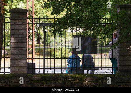Due donne sedute su una panchina e una in piedi fuori dal Kopli Cemetery Park a Tallinn Estonia Foto Stock
