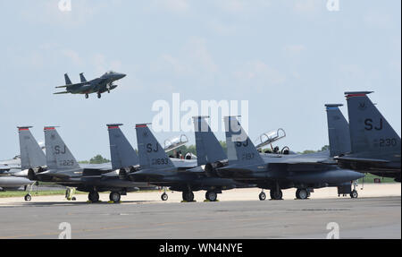 Un F-15E Strike Eagle dal 4° Fighter Wing, Seymour-Johnson Air Force Base in North Carolina, sull approccio finale di Tinker AFB, Oklahoma con altri Strike Eagles parcheggiato in primo piano durante una massa-trasferimento di aeromobili vulnerabili per sfuggire uragano Dorian il percorso sett. 4, 2019, Tinker AFB, Oklahoma. Team Tinker eseguito un accordo esistente con Seymour-Johnson AFB, North Carolina e Warner-Robins AFB, Georgia per ospitare i combattenti, petroliere e aerei di ricognizione lontano dal devastante uragano attualmente che influiscono sulla costa est degli Stati Uniti. (U.S. Air Force foto/Greg Foto Stock