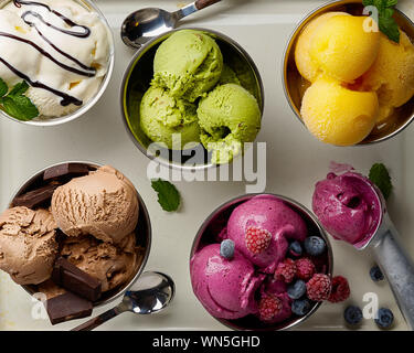 Un assortimento di sapori e colori di gourmet gelato italiano servito sul tavolo in acciaio. Mango, cioccolato, Verde matcha ice cream Foto Stock