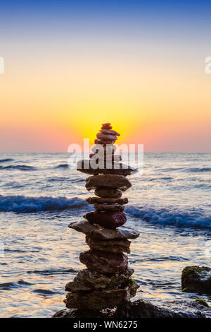 Zen ciottoli di bilanciamento. Pila di ciottoli sulla spiaggia con sunrise sullo sfondo Foto Stock