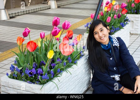 I viaggiatori tailandese donne in posa e ritratto con tulipani fiore in giardino nella parte anteriore del Tokyo Big Sight a Koto città in Tokyo, Giappone Foto Stock