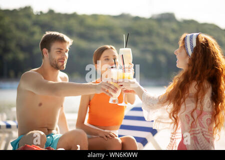 Amici sorridere mentre bevendo cocktail estivo insieme Foto Stock