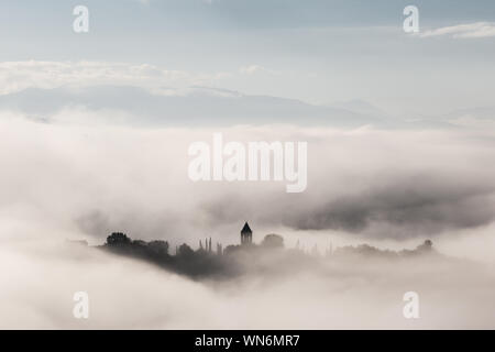 Vista surreale di Mora town (Assisi) quasi completamente nascosto dalla nebbia Foto Stock