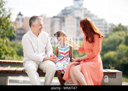 Amare i capelli rossi foster mom toccando il naso della sua ragazza carina Foto Stock