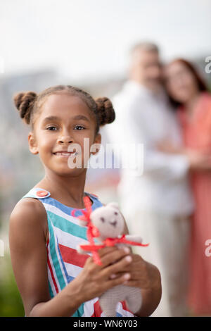 Bella figlia afro-americana con il suo giocattolo preferito Foto Stock