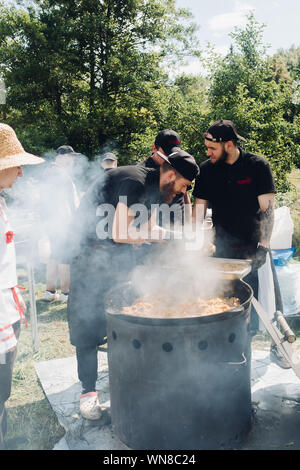 Gli uomini di mettere pilaf dal calderone nel contenitore. Foto Stock