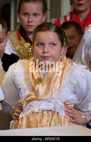 Ragazza vestita in regionali tradizionali costumi folk in chiesa durante la Santa Messa il giorno del Ringraziamento in Stitar, Croazia Foto Stock