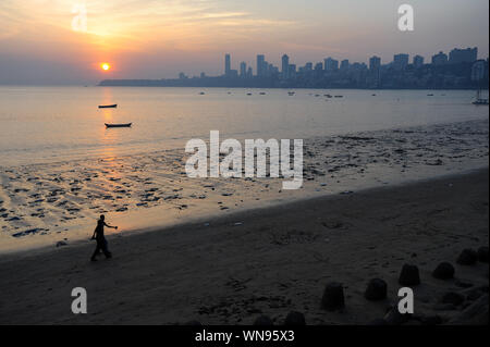 12.12.2011, Mumbai, Maharashtra, India, Asia - Tramonto sulla spiaggia di Chowpatty lungo Marine Drive con la silhouette del Malabar Hill lo skyline della citta'. Foto Stock