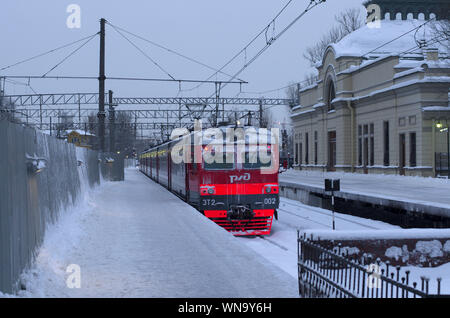 Vitebsky stazione ferroviaria,Saint Petersburg, Russia - 24 Gennaio 2019: il rosso-arancione treno RZD sorge sulla coperta di neve via nei pressi del vecchio edificio che io Foto Stock