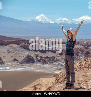 Vista posteriore di attiva donna in piedi con le mani spalancate, femmina assolo di spensierata traveler in hat e abbigliamento casual di ammirare splendidi paesaggi della luna Foto Stock