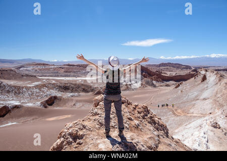 Vista posteriore di attiva donna in piedi con le mani spalancate, femmina assolo di spensierata traveler in hat e abbigliamento casual di ammirare splendidi paesaggi della luna Foto Stock