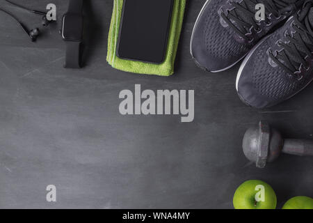 Fitness uno stile di vita sano e la perdita di peso del concetto. Vista superiore dell'atleta dumabbell attrezzature, smartphone smart watch, scarpe sportive e mela verde su Foto Stock