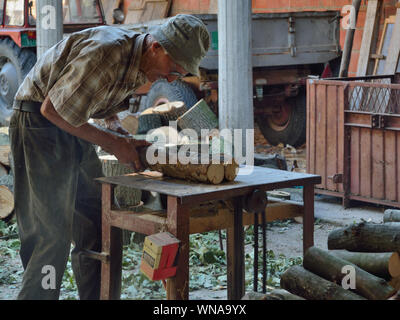 Uomo anziano che usa vecchio tavolo sega circolare per tagliare legno. Europa, Serbia Foto Stock