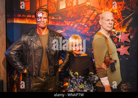 Inghilterra, Londra, Marylebone, vista interna della signora Tussauds, turistico in posa con Waxwork figure di Arnold Schwarzenegger e Bruce Willis Foto Stock