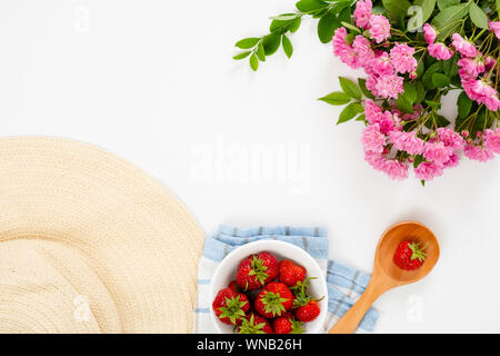 In estate la colazione del mattino concetto con Fragola, cappello di paglia, il cucchiaio di legno, rosa rose fiori. Appartamento laico, vista dall'alto, overhead. Foto Stock
