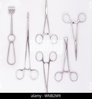 Primo piano di strumenti chirurgici in acciaio su sfondo bianco Foto Stock