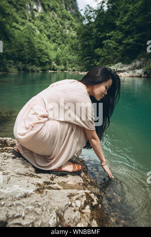 Una ragazza tocca l'acqua in un fiume o stagno o lago. Unità con la natura. Foto Stock