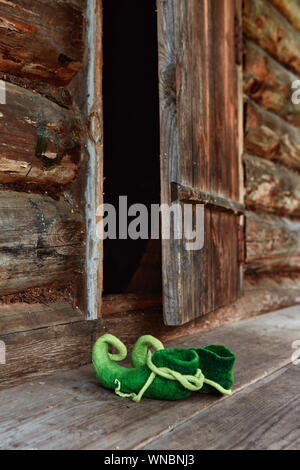 Una creatura Fairy elf o foresta dwarf lasciato le sue scarpe sulla soglia di una vecchia casa in legno nei pressi della porta anteriore Foto Stock