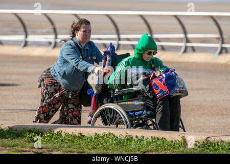 Blackpool, Lancashire, Regno Unito. 06 Sep, 2019. Figlia di spingere un anziano rispetto al vento sul lungomare. Credito: MediaWorldImages/Alamy Live News Foto Stock