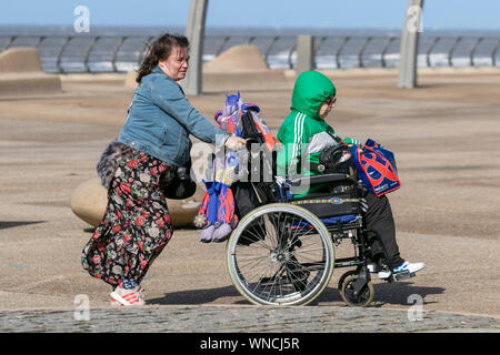 Blackpool, Lancashire, Regno Unito. 06 Sep, 2019. Figlia di spingere un anziano rispetto al vento sul lungomare. Credito: MediaWorldImages/Alamy Live News Foto Stock